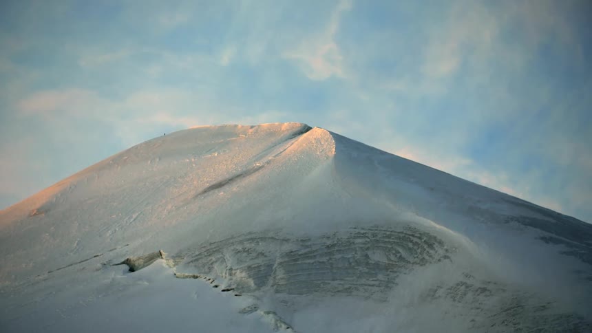 A mountain top is covered in a thick blanket of snow