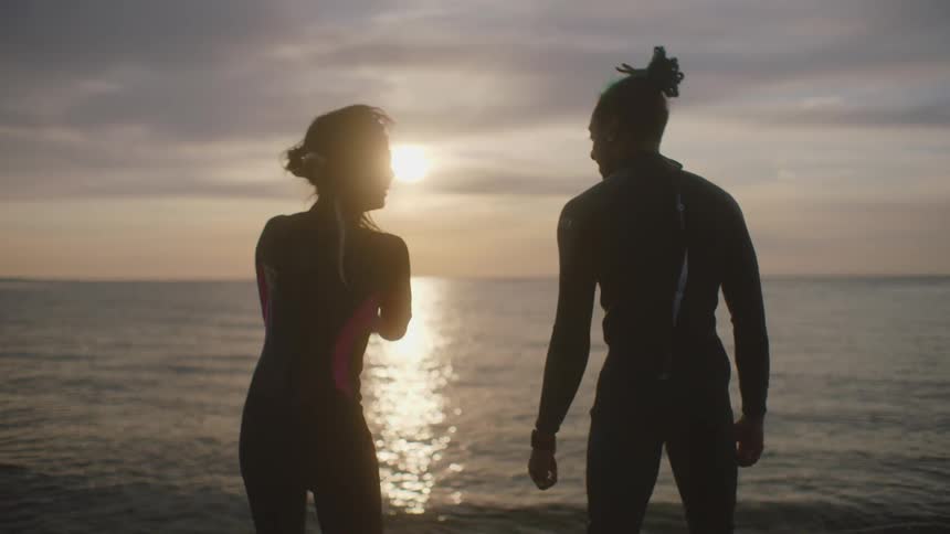 A man and woman stretch while working out near the ocean