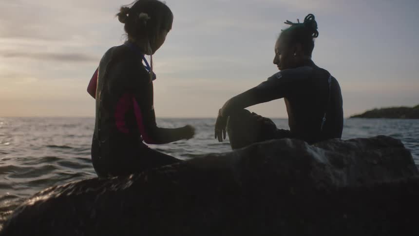 A man and woman sitting outside next to the ocean