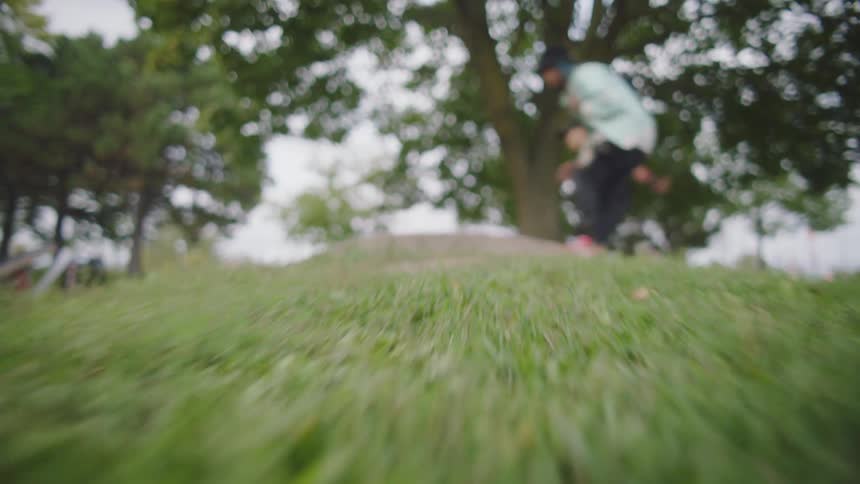 Two teenagers skate over a small hill outside