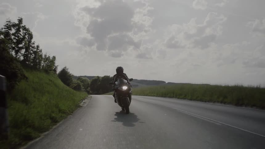Person riding a motorcycle down a country road