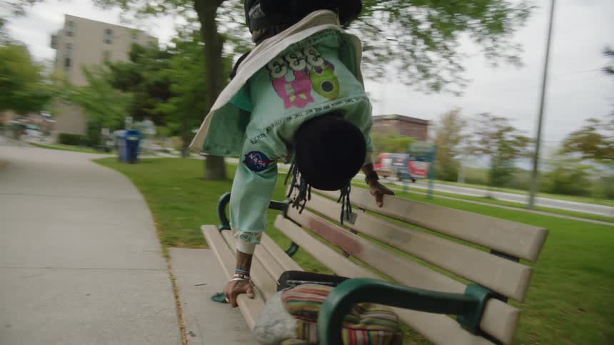 Young man doing a hand stand over a benck in the park
