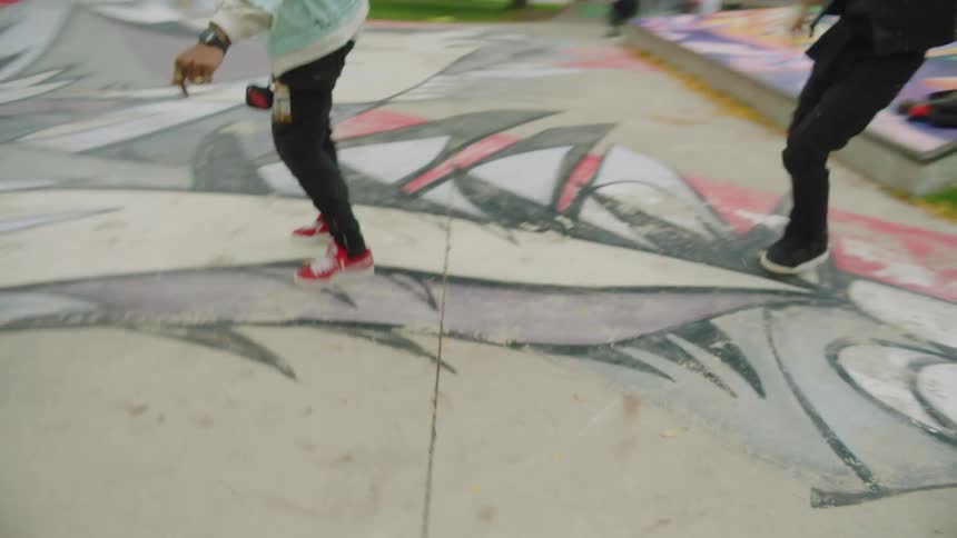 A man and woman do a choreographed dance in a skate park