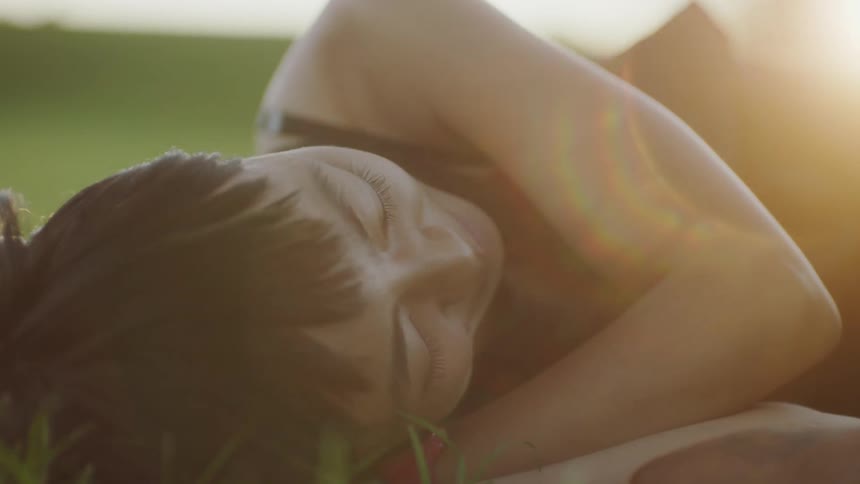 Woman lies on lawn smiling on sunny day