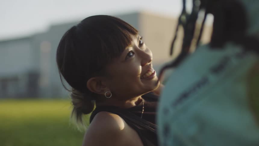 A woman smiles at her boyfriend as they lie in the grass