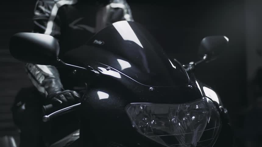A man in black gets on a motorcycle