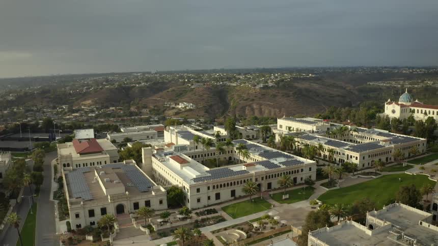Square buildings with palm trees in center courtyards with green grass lawns and play area