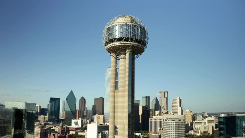 The reunion tower in dallas texas with city skyline behind under a cloudless sky