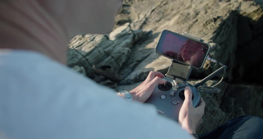 A man is holding a remote control device in his hands