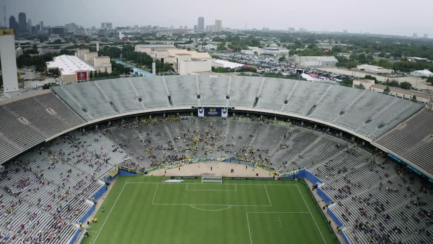 A crowd sits scattered throughout a football stadium near downtown