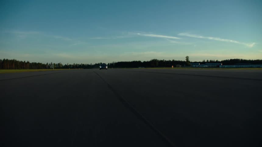 A car drives fast down an empty road