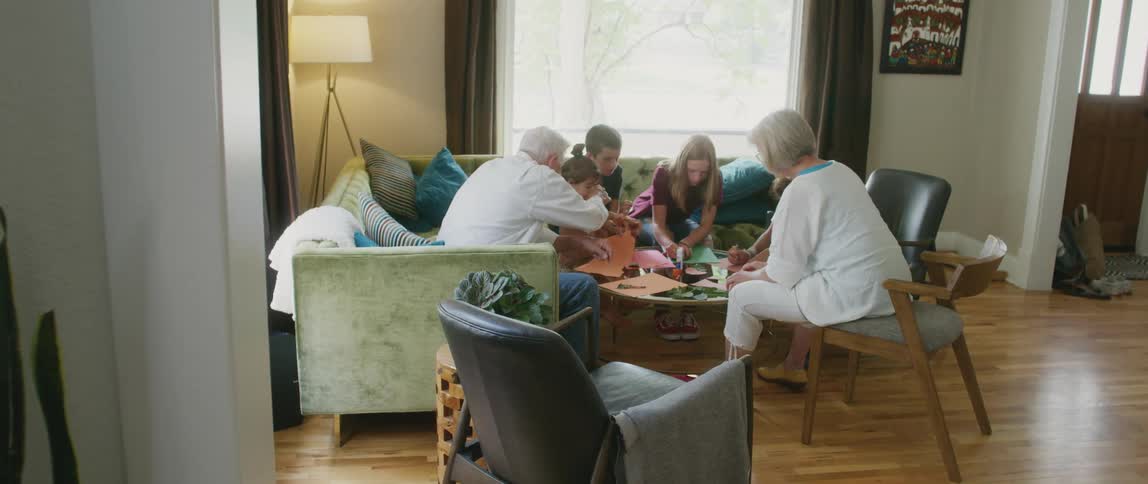 A family is in their home making decorations from colored construction paper