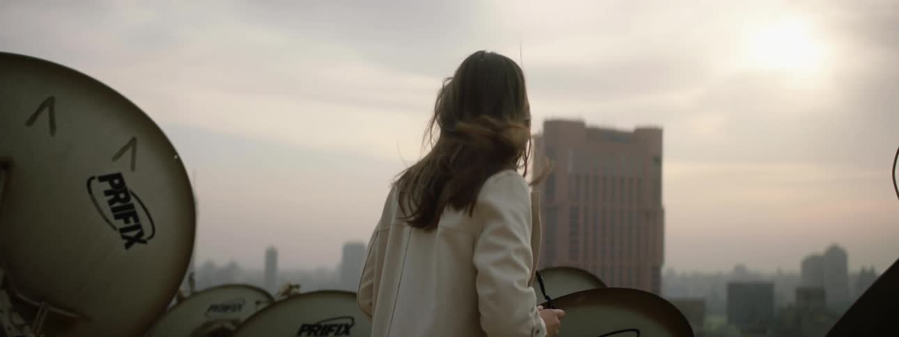 Woman stands on roof taking pictures of foggy city