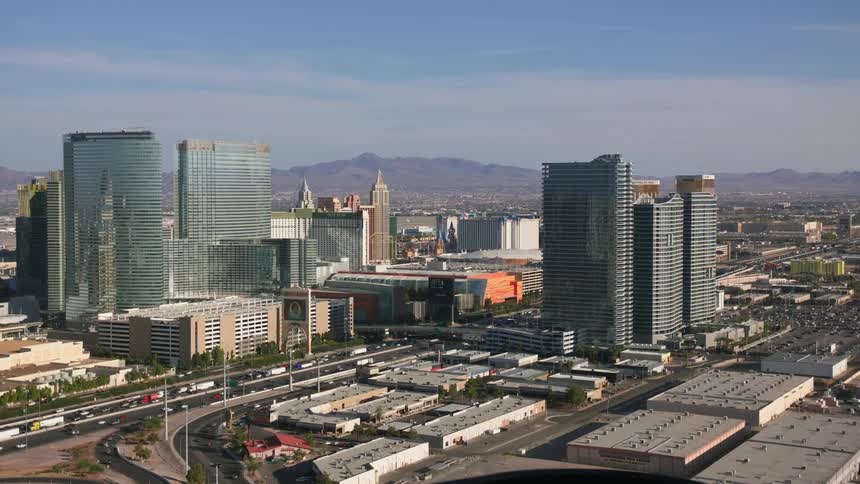 Traffic flows along highway through downtown during rush hour as city stretches to foggy mountains