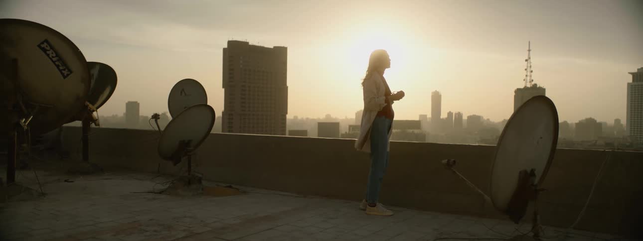 A woman takes photos of downtown from her buildings rooftop