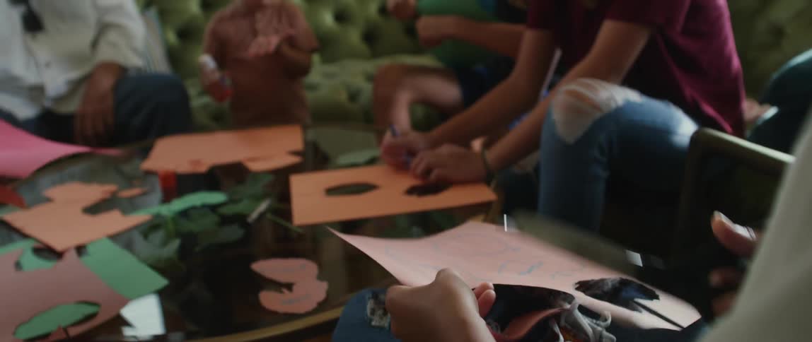 A group of mixed age and race children cutting out paper leaves with words written on them