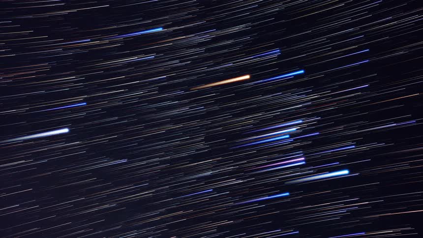 The stars and constellations in the night sky blur and elongate