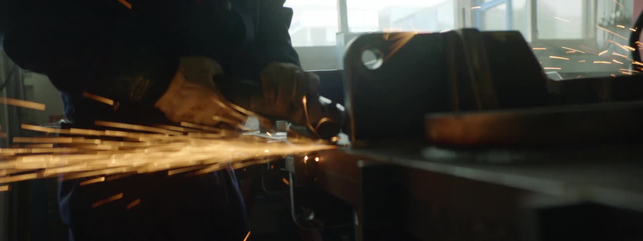 A man is using a grinding tool to cut metal