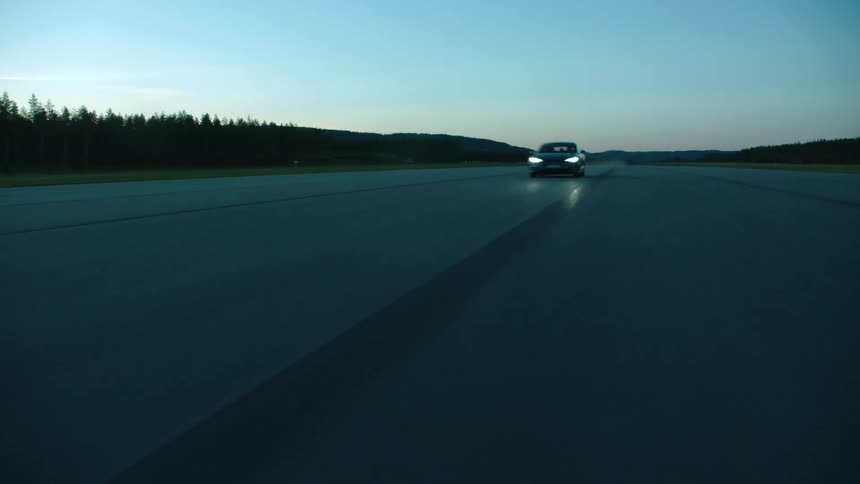 A sports car speeds down the middle of a track