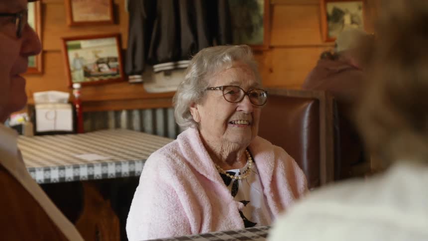 Elderly couple sitting at a table in a restaurant talking to friends