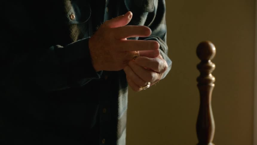 A man puts on his wedding ring in the bedroom