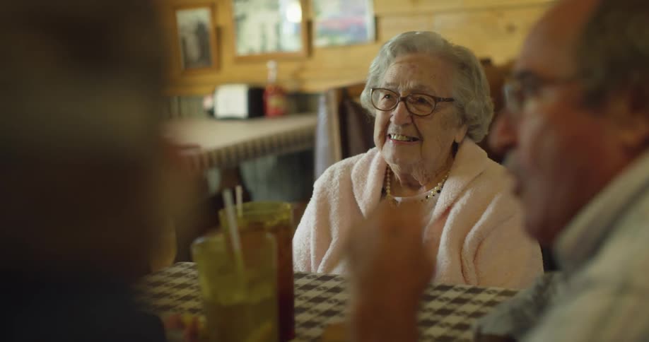 Elderly couple sitting on a restaurant eating and talking with friends
