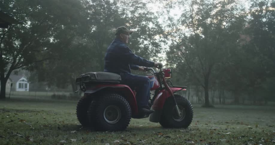 Man rides three wheeler across fallen leaves strewn yard