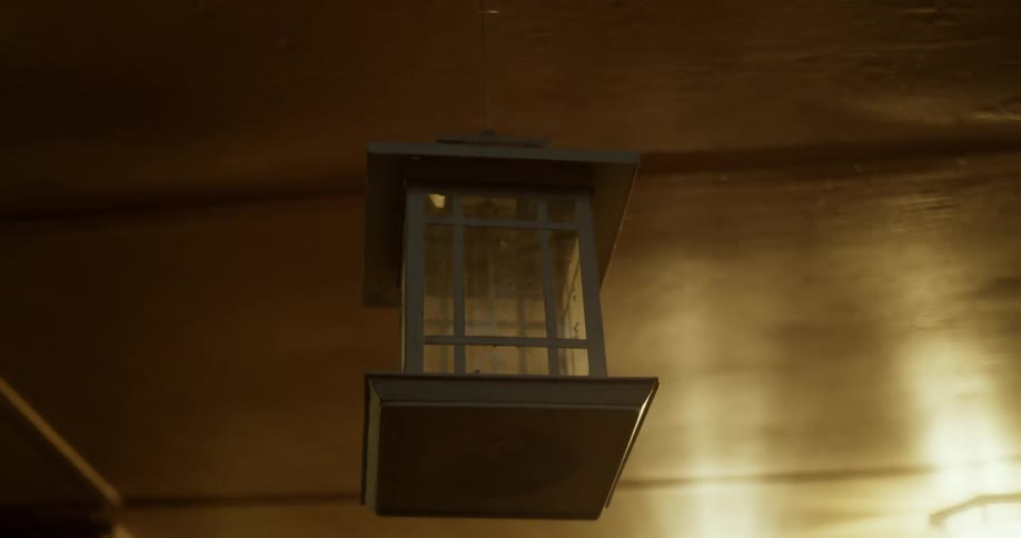 Square wooden hanging lamp sways in the breeze