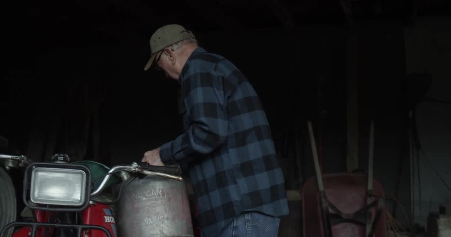 Person putting fuel in bike in a dark shed