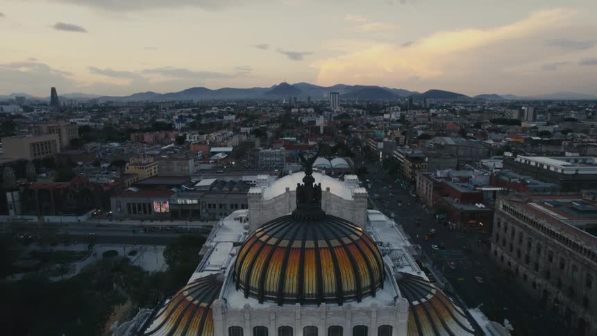 An aerial view of large dome shaped building in a city with cars driving past