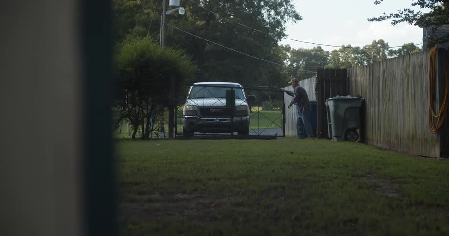 A man is outside opening a gate