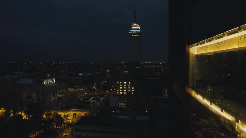 A tall skyscraper looms over a metropolis at night