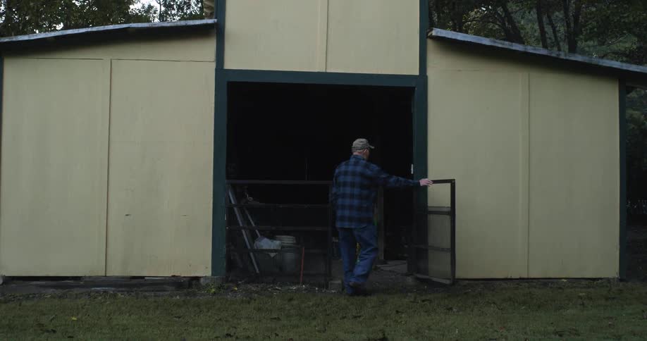 Elderly man going into an old barn