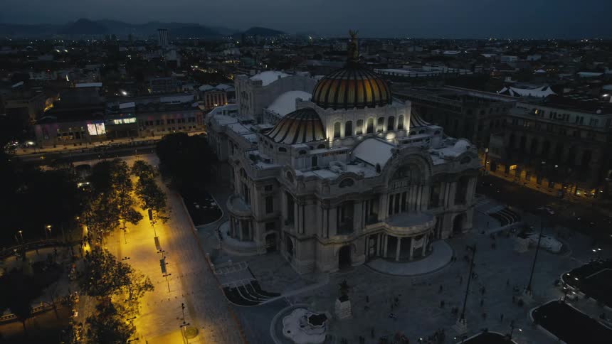 An aerial view of a government building at night as cars drive past