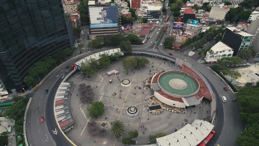 People are walking around the center as the vehicles travel on the round road
