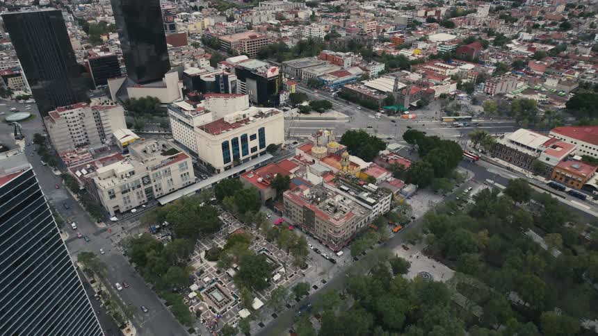 Cars travel on wide city streets past skyscrapers and buildings