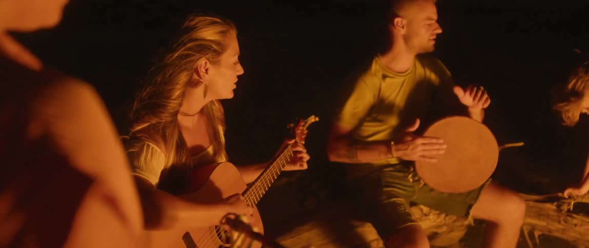 A view of people playing instruments around a fire