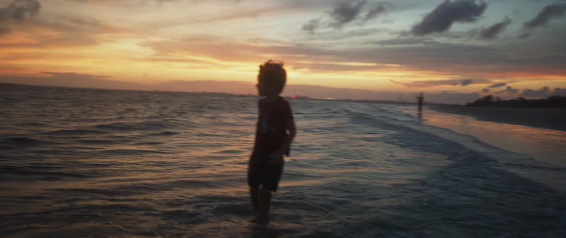 Silhouette of a young boy playing on the beach at sunset