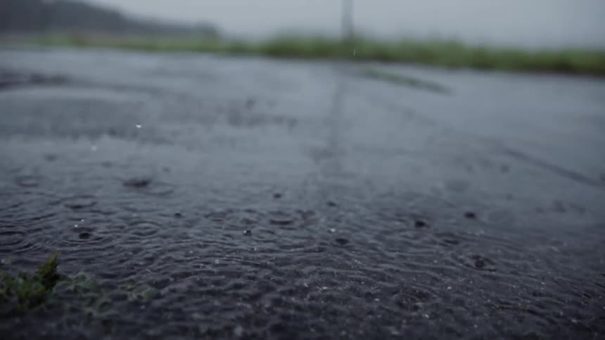 Rain slowly falls on gravel and splashes around