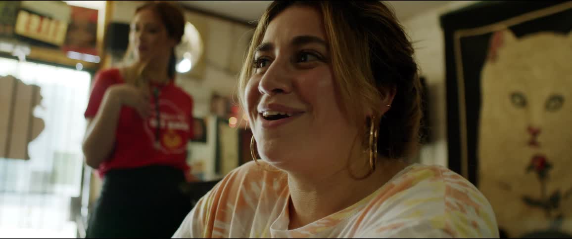 A woman laughs in an eclectic restaurant as a waitress walks behind her