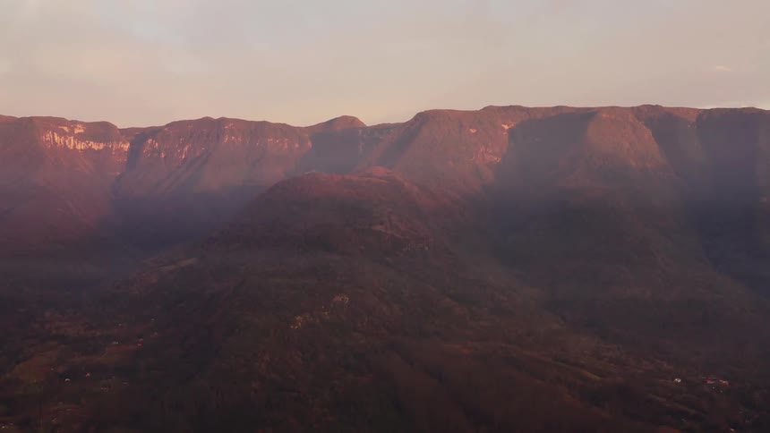 Aerial view of sun shining on distant mountain tops and valley