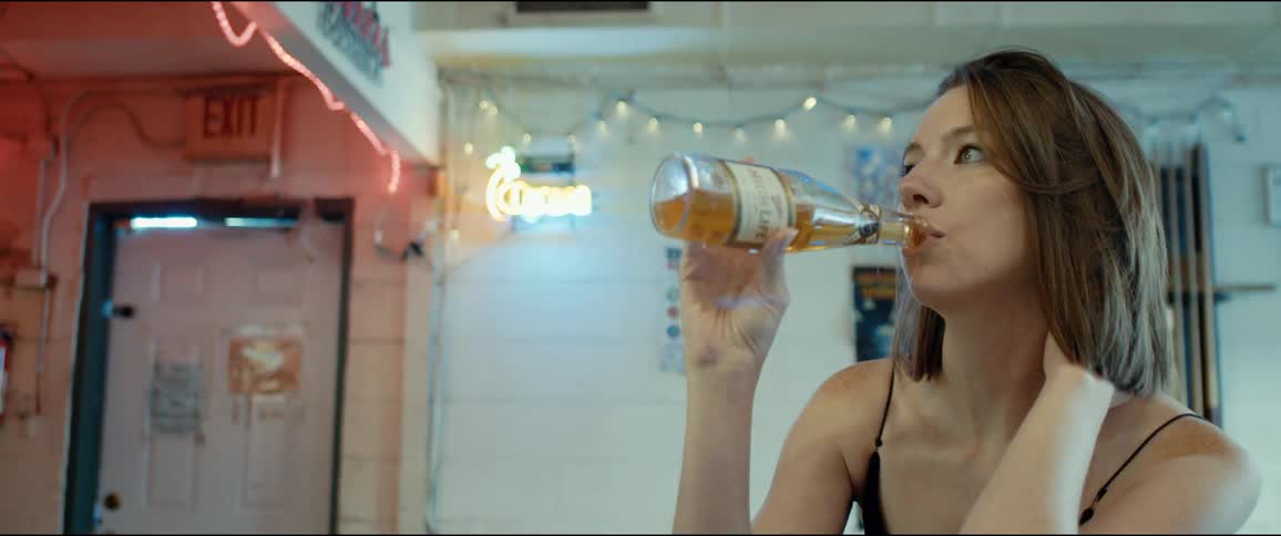 Young woman sitting at a table in a restaurant drinking a beer