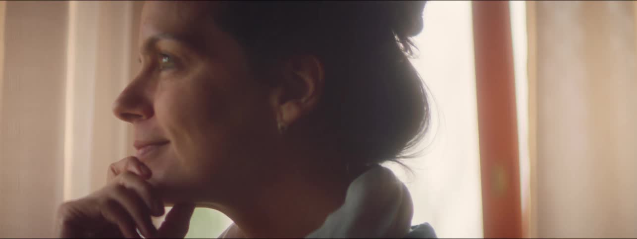 Woman happily gazing outside with hand on chin