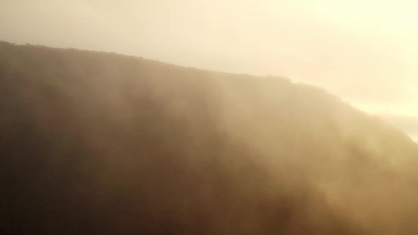 An aerial view of a hill with mist and fog around it