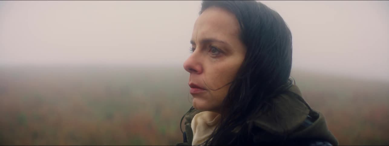 Woman stands outside near fog covered autumn forest breathing deeply