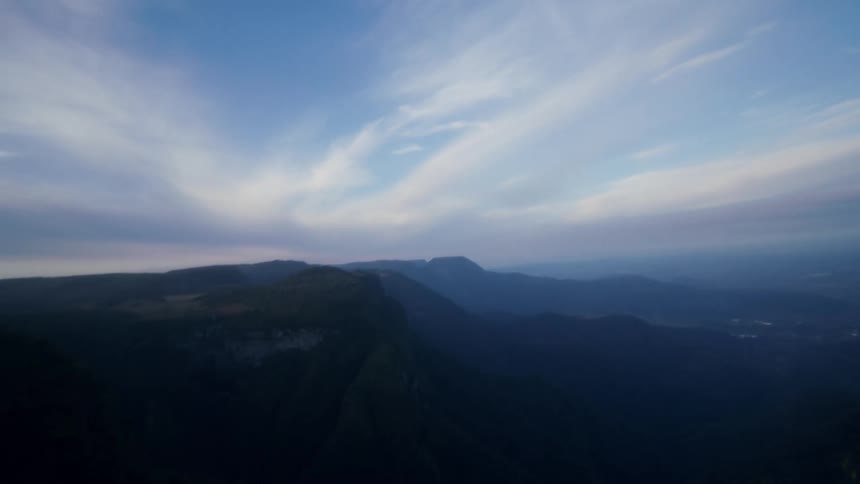 A wide angle view of a mountain range and canyon at dusk