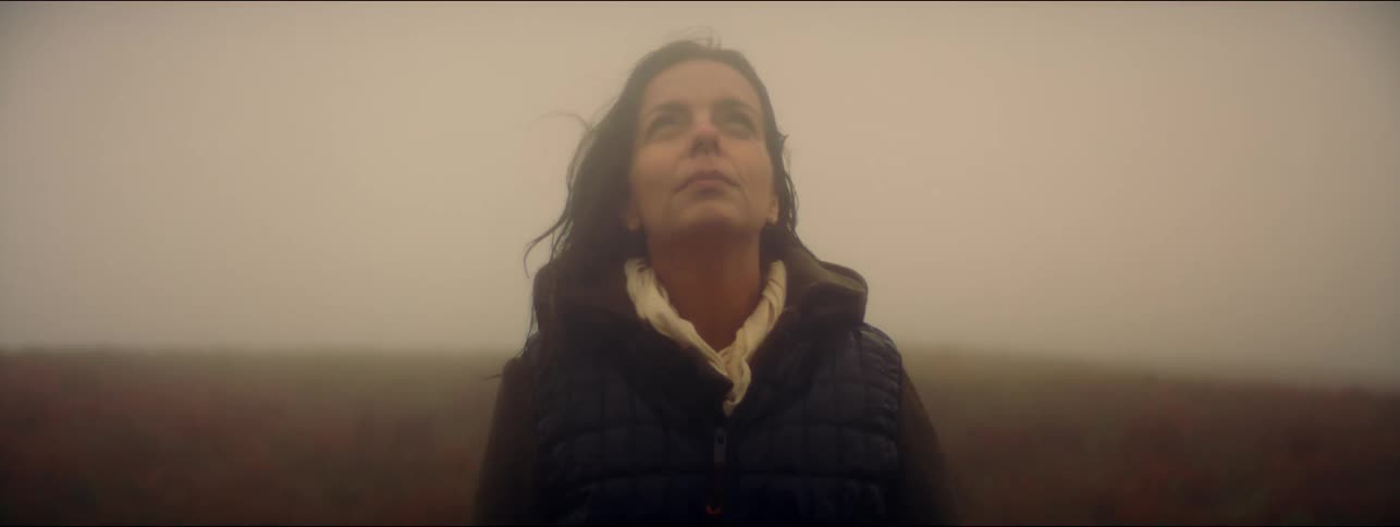 Woman stands outdoors on windy day closing her eyes