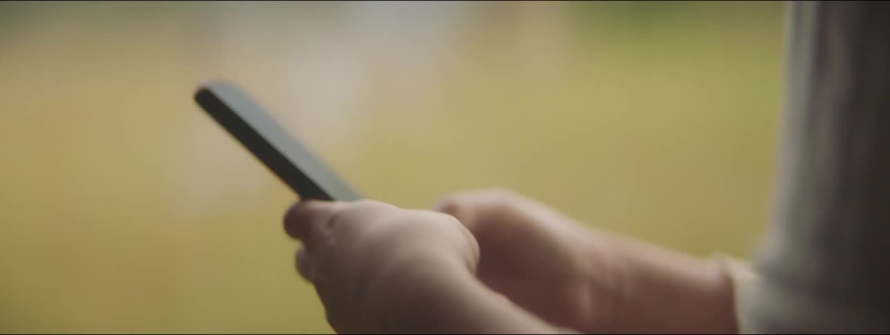 A woman is holding and texting on a cell phone outside