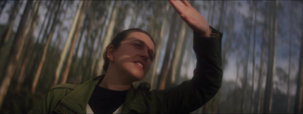 Woman standing on a forest covering her face from the sun with hand