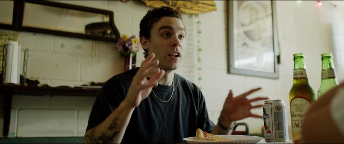 A man talks with a companion sitting across from him at a table in a restaurant